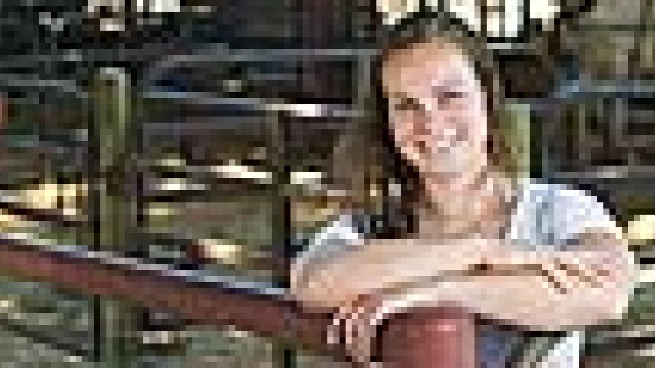 Woman in a livestock pen, posing for the camera