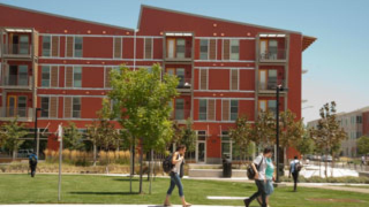 students disembark from a bus at West Village at UC Davis