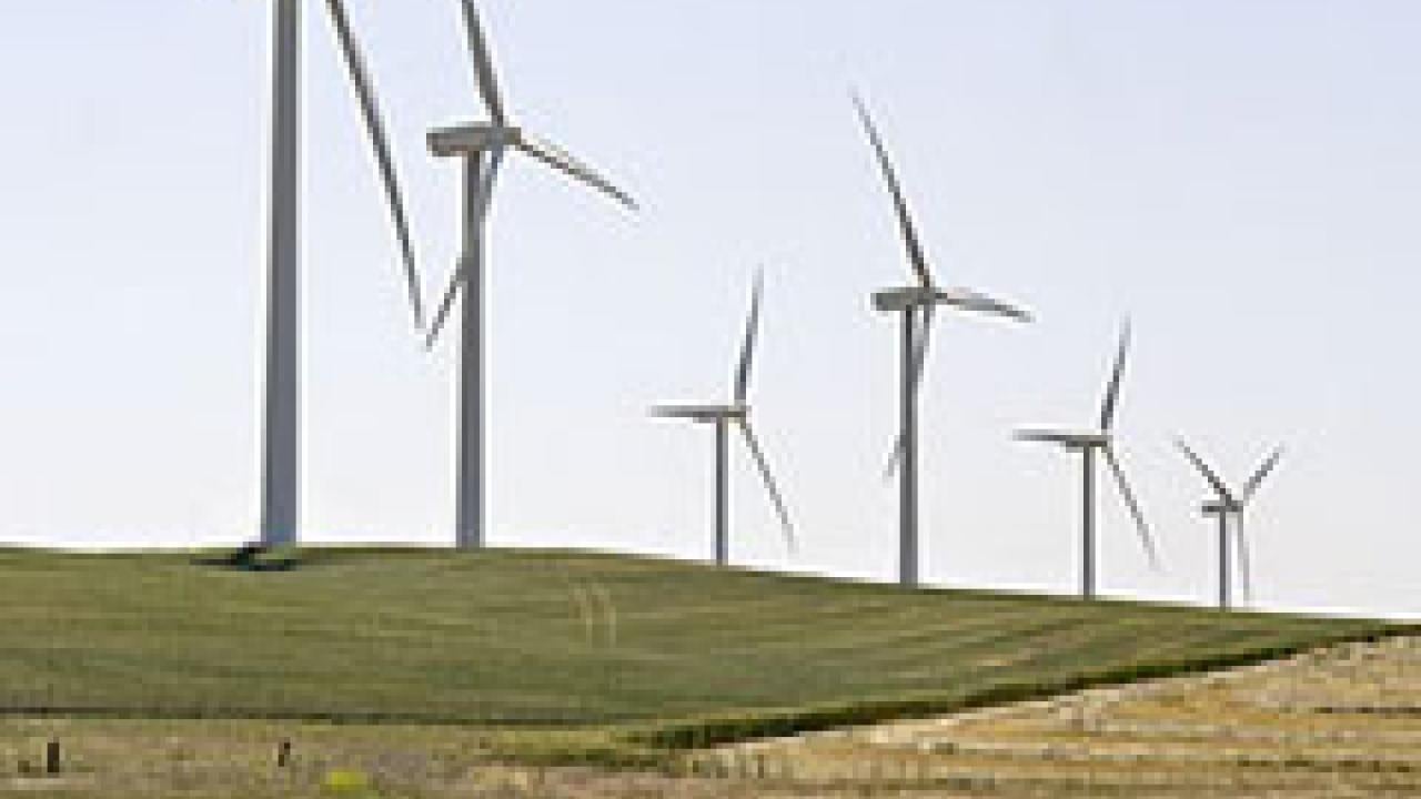 Photo: Wind turbines on a hill with a rural fence in foreground
