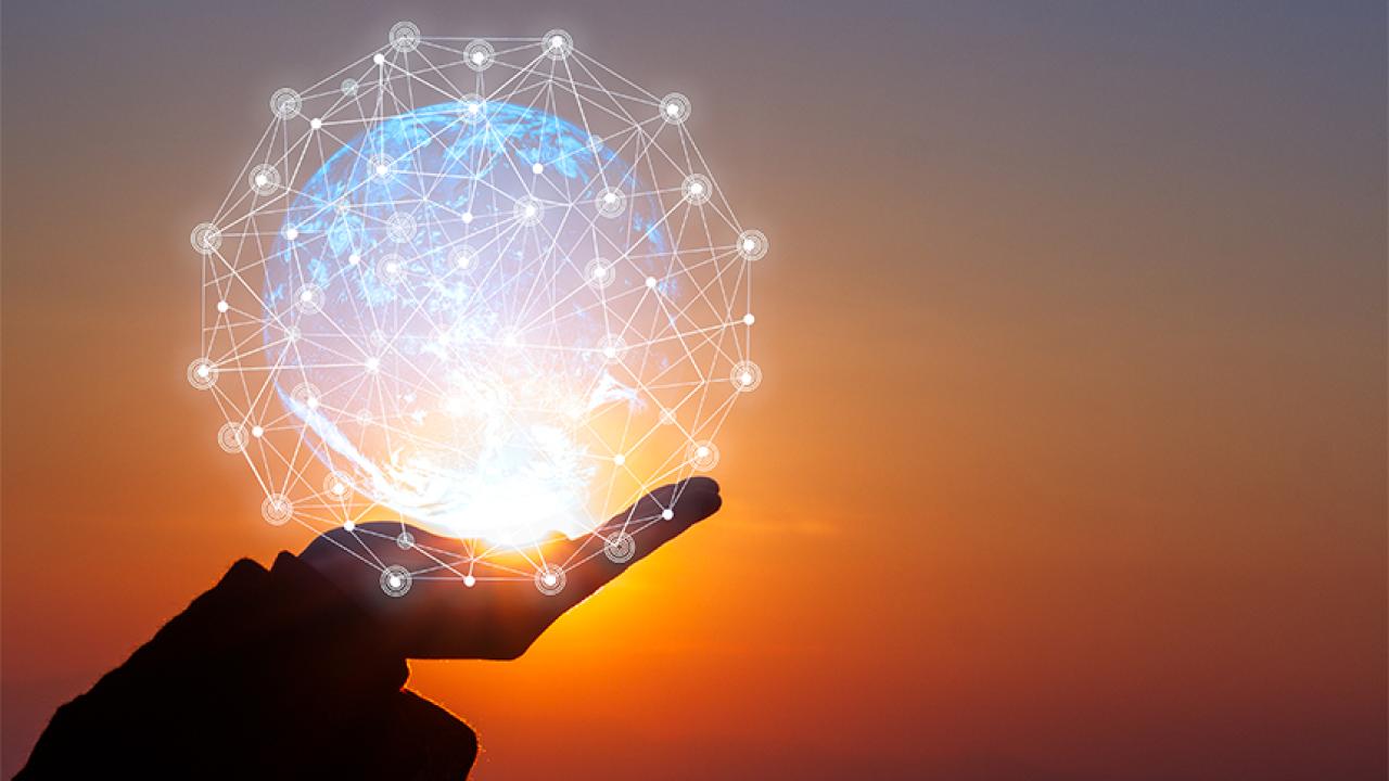 A lighted globe in a hand against sunset