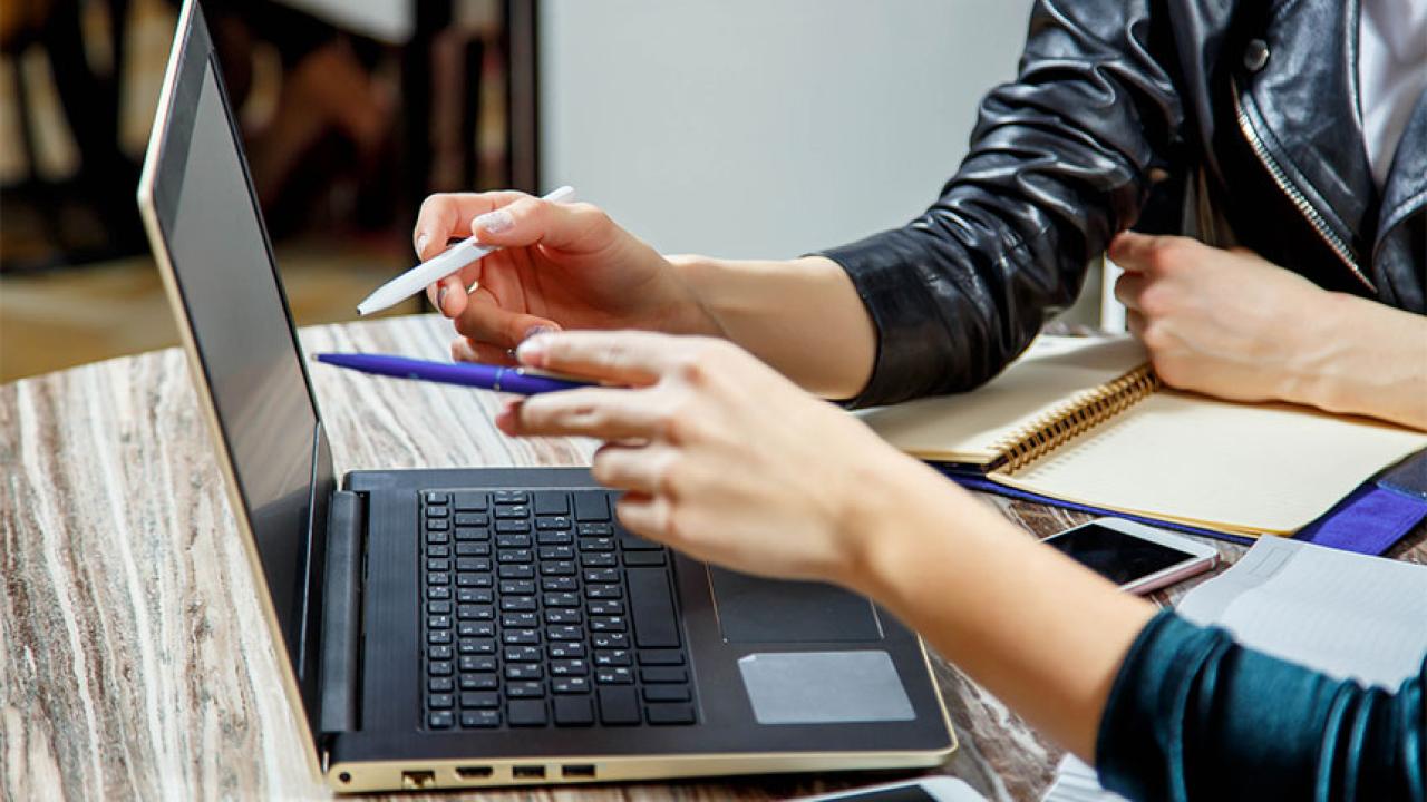 Closeup of two people pointing at laptop screen