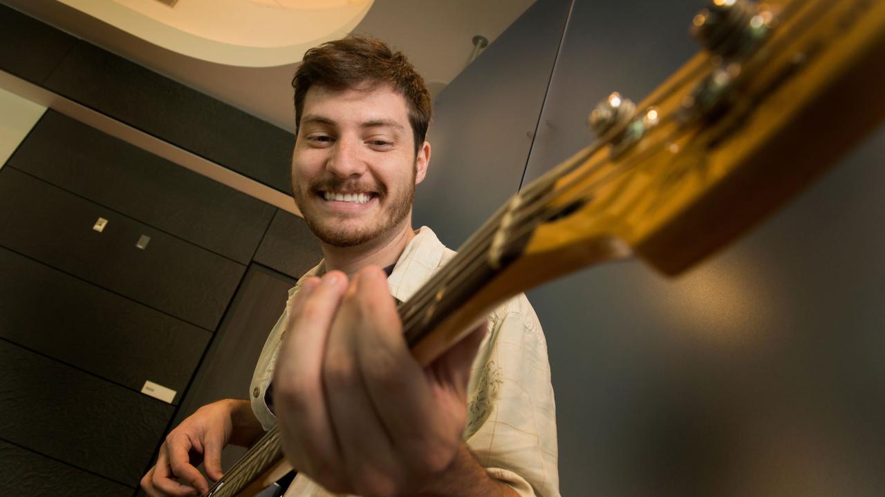 Male student playing a guitar