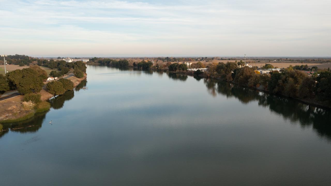 A view up a broad river with a small town on the right bank. 