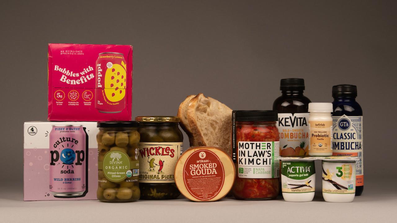 A variety of food products that may or may not be probiotic, prebiotic, or just contain good microbes. They include soda, olives, kimchi, yogurt, pickles, cheese, kombucha and sourdough bread. (Greg Urquiaga/UC Davis)