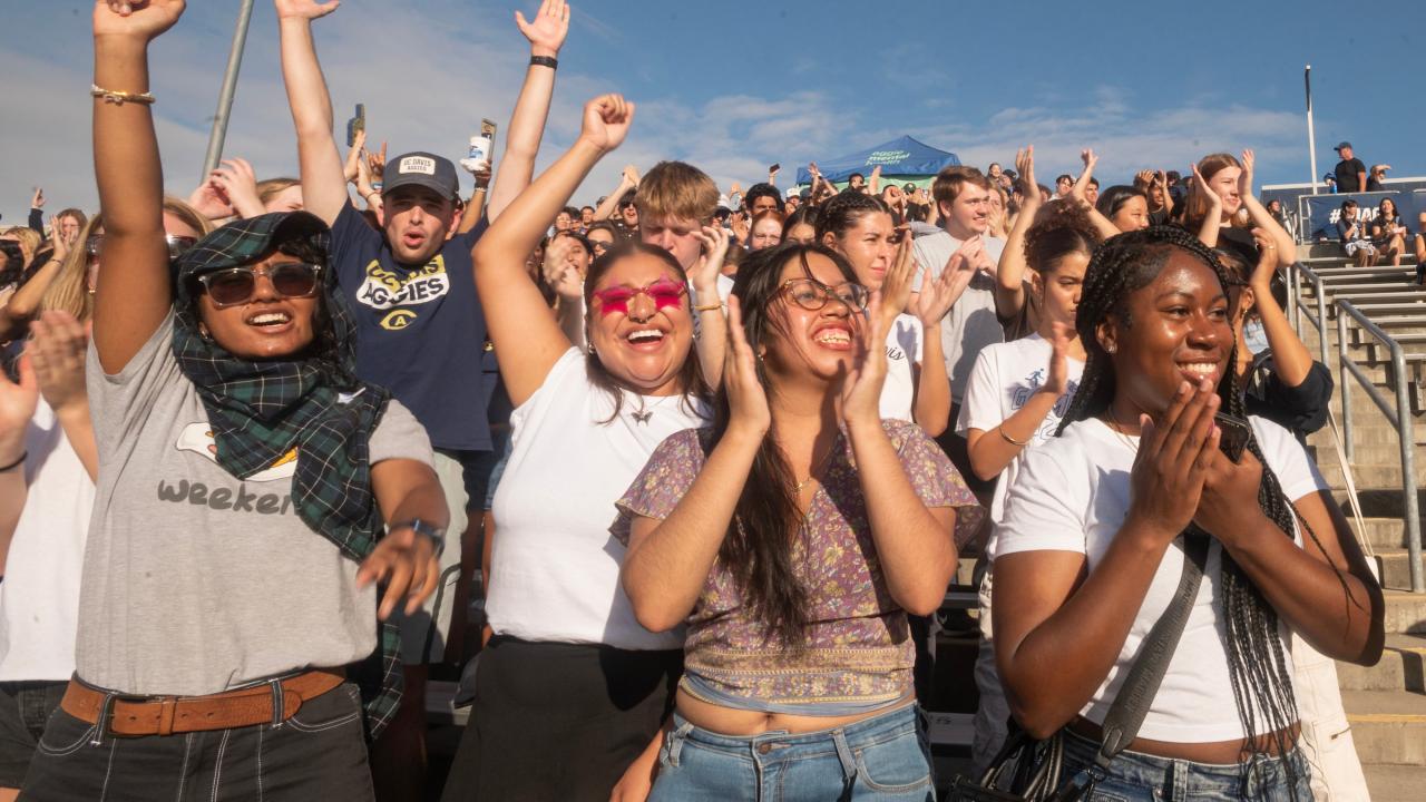 A diverse group of smiling young people outdoors in sunshine 