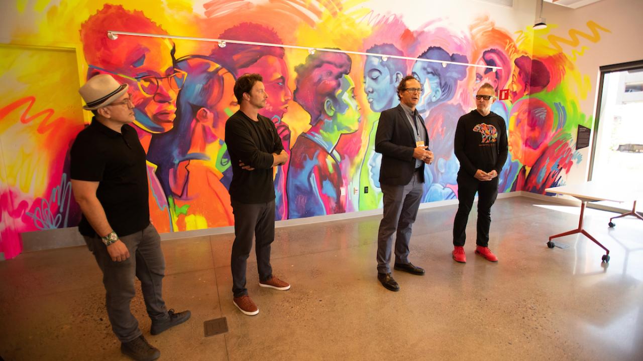 Artists stand in front of mural.