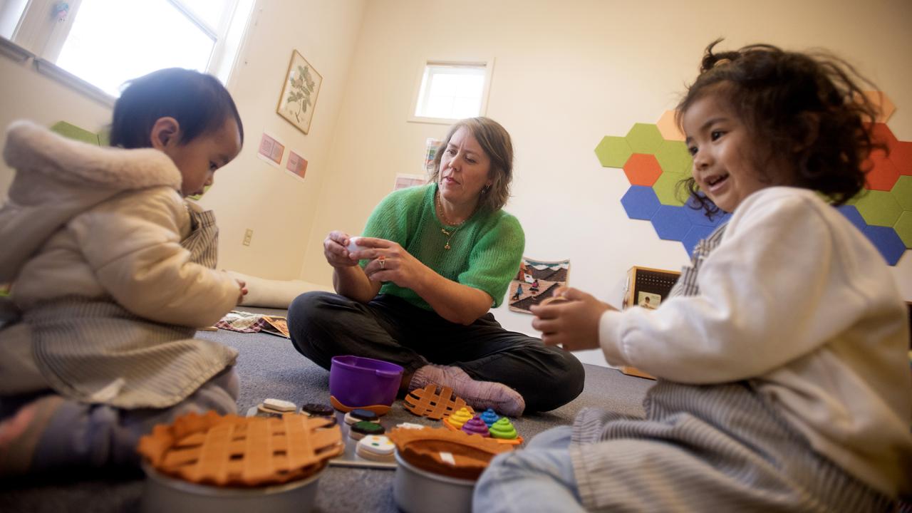 2 kids playing with a teacher with toys