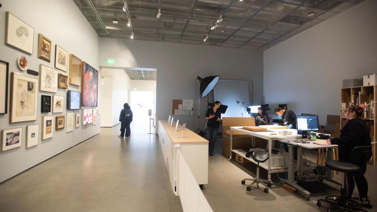 A spacious gallery with framed artwork on the walls; a reception area in the foreground.