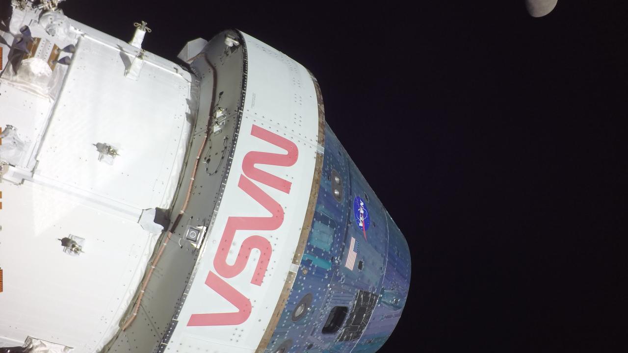 A spacecraft with the text "VSN" and "NASA" against a dark sky, with the moon in the background.