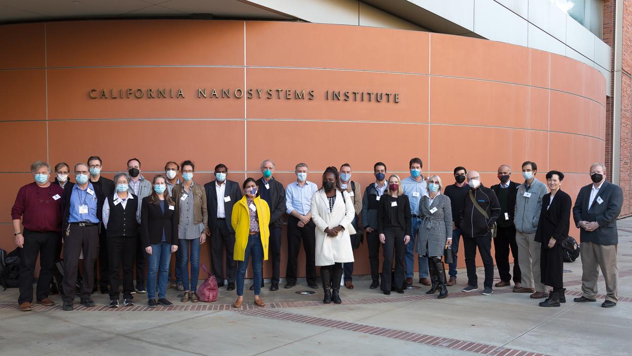 Group of people standing outdoors in front of an orange wall 