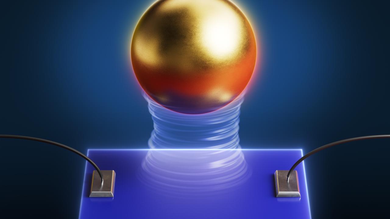 A shiny gold sphere hovers above a blue rectangular plate. Wires are attached to the plate at left and right. 