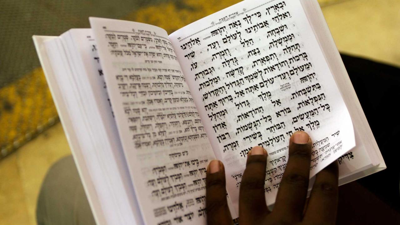 Black hand holding open sidur