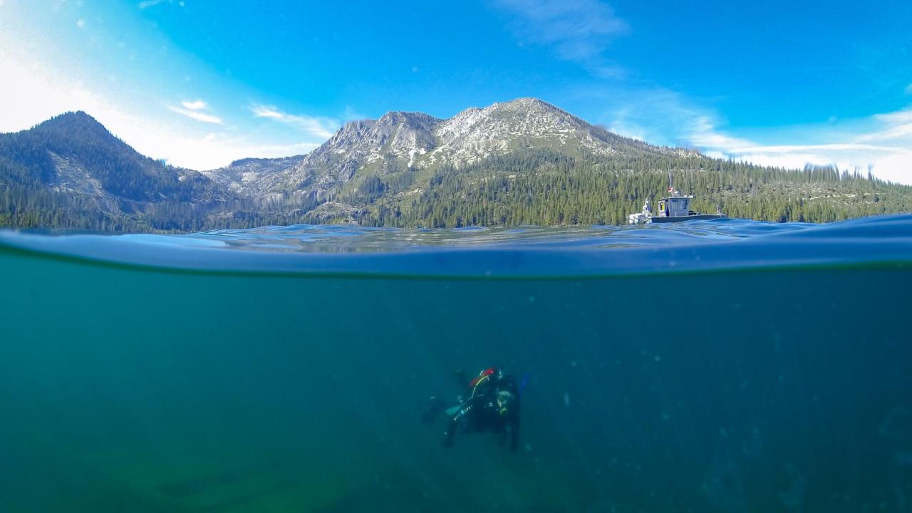 Diver Katie Senft seen underwater Lake Tahoe while mountain and sky are above