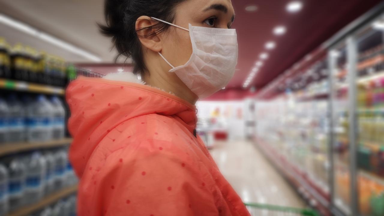 Woman wearing mask looks at groceries in store