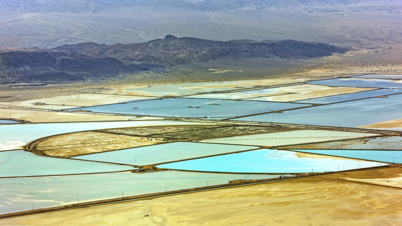 Aerial view of a desert landscape with bright blue squares in the center. 