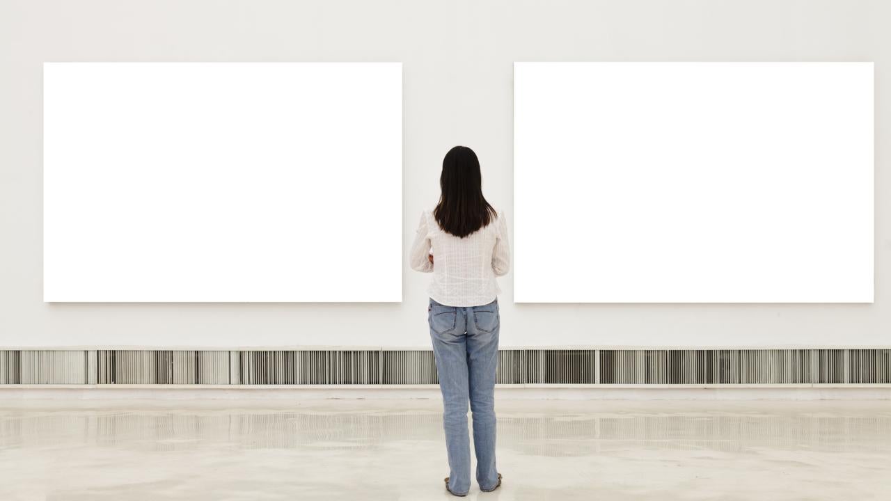 Woman standing in front of blank canvases in exhibit space