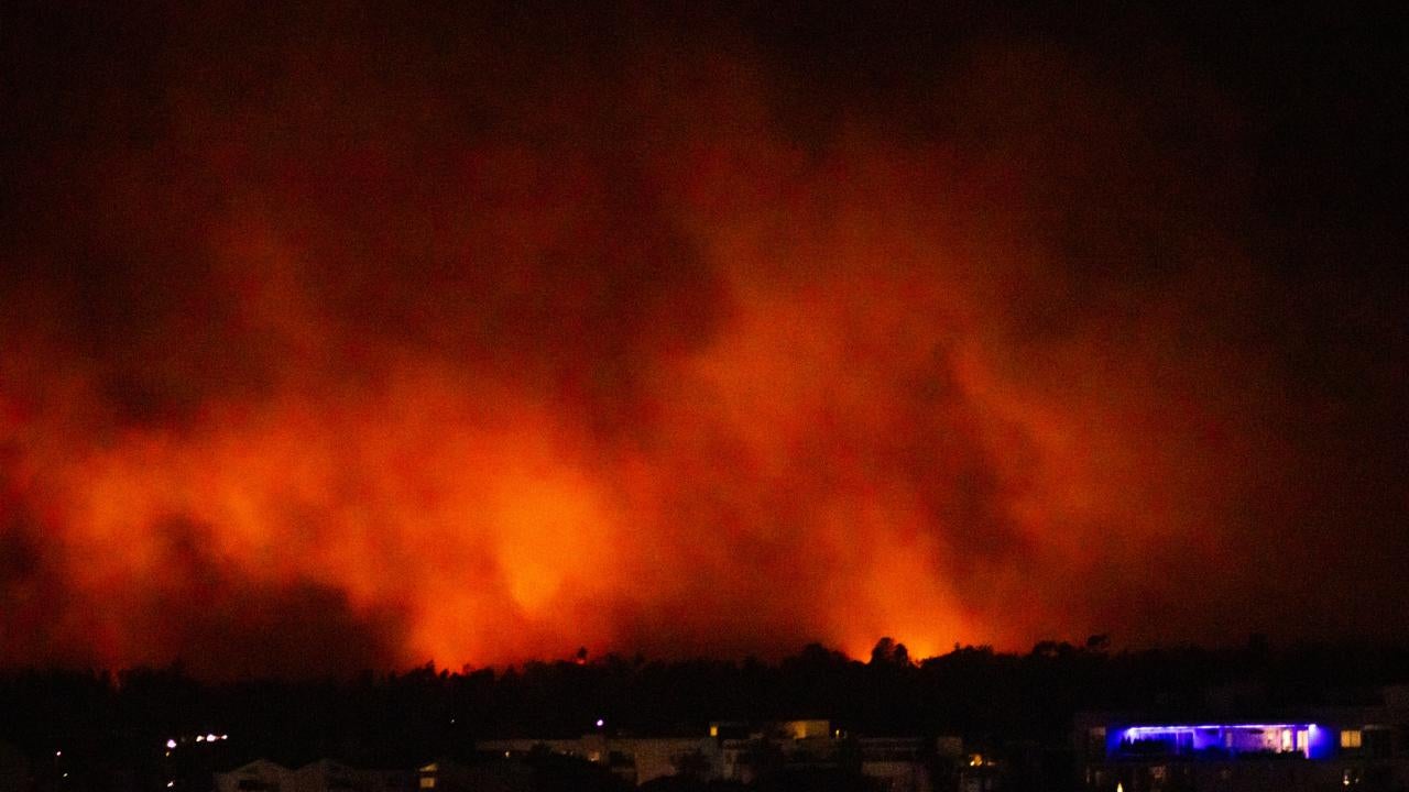Plumes of fiery smoke from the Pacific Palisades Fire at night 