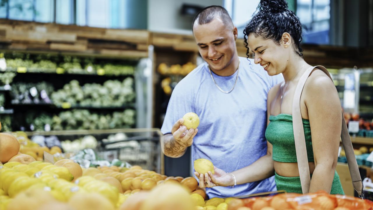 Couple of people in grocery store looking at produce 