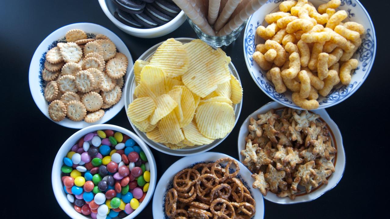 In this episode of Unfold, we uncover the science and debate behind processed and ultra-processed foods. Shown here are eight bowls with various processed and ultra-processed foods, including chips, pretzels and candies.(Getty)