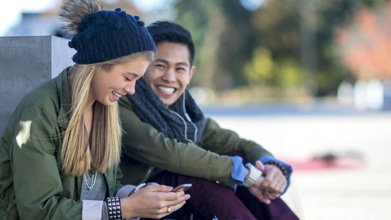 Young couple wearing jackets talking to each other outdoors