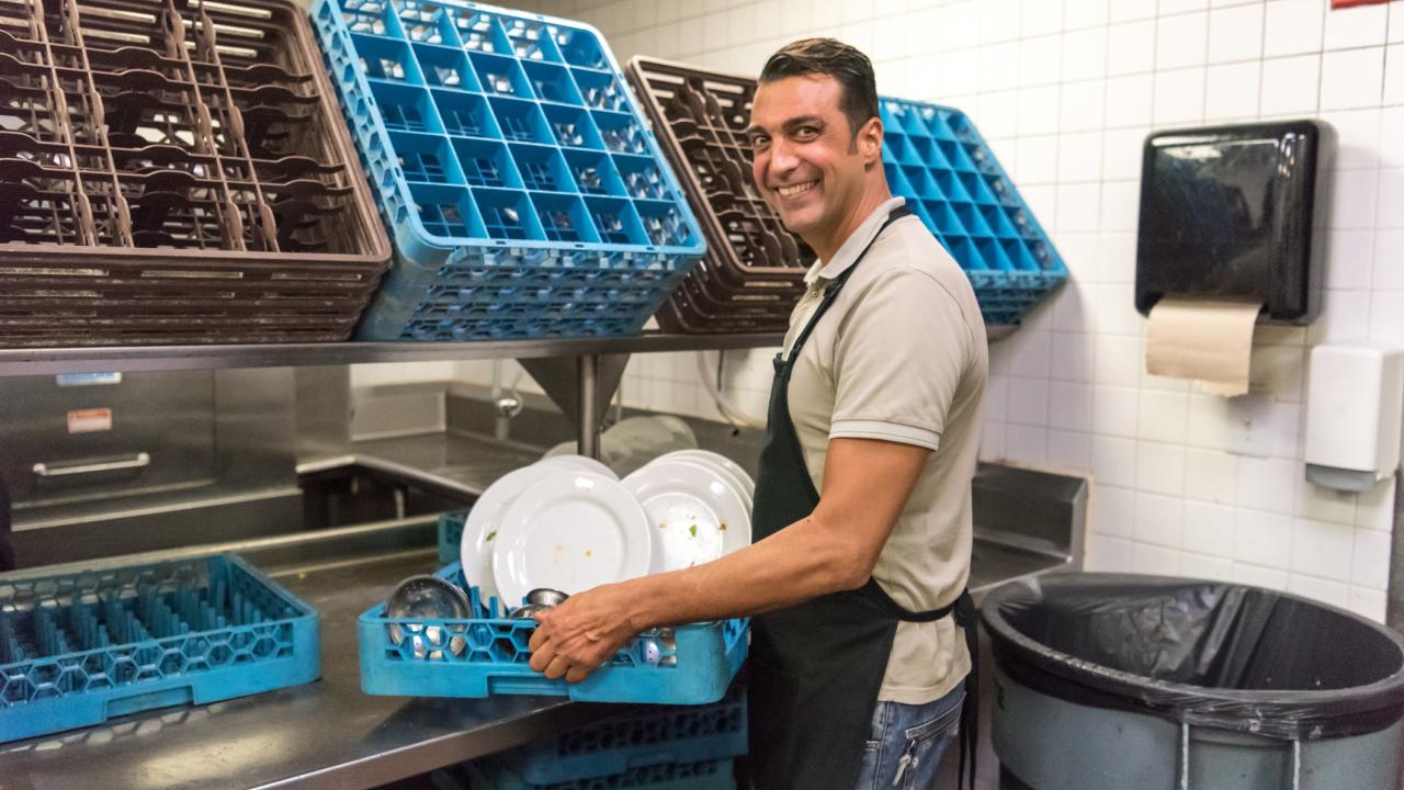 Man working among dishes in back of restaurant
