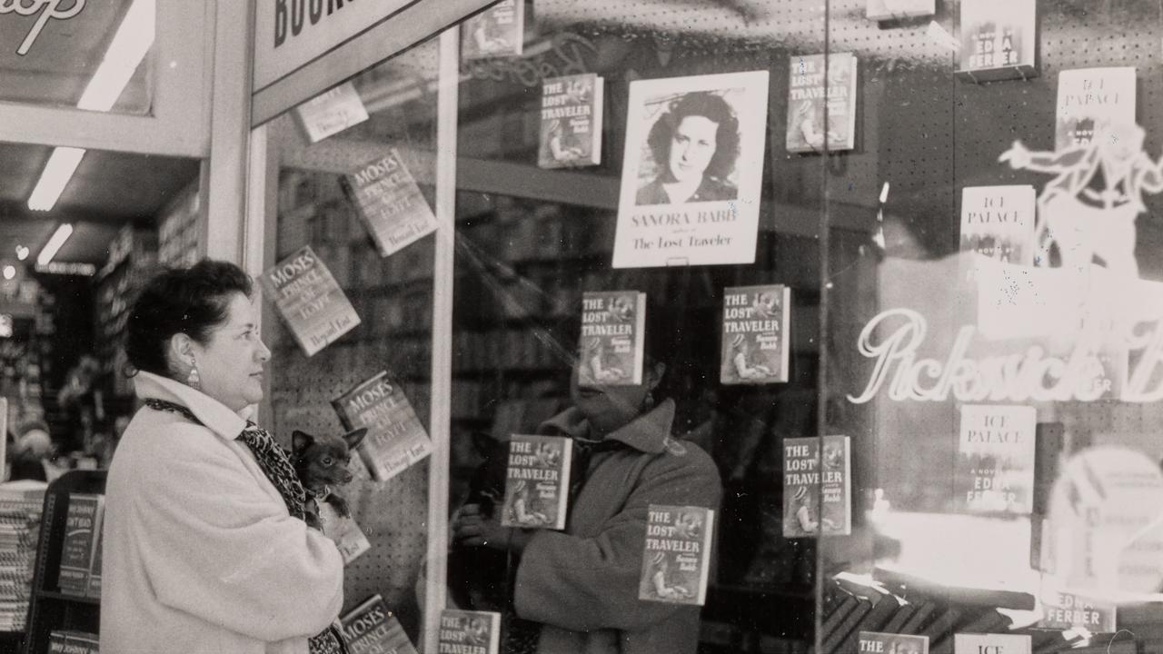 Black and white photo of woman looking in bookstore window of her own book