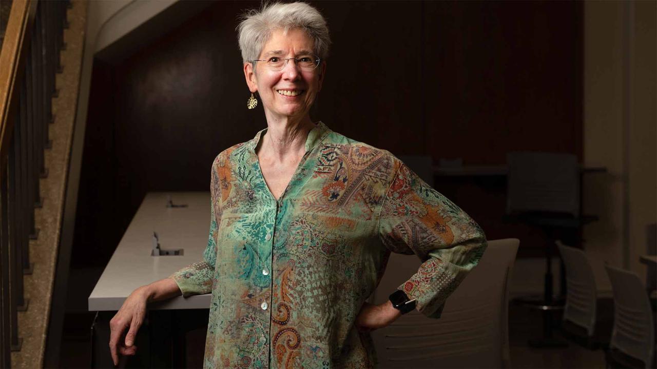 Johanna Schmitt  leans against a staircase inside a building.