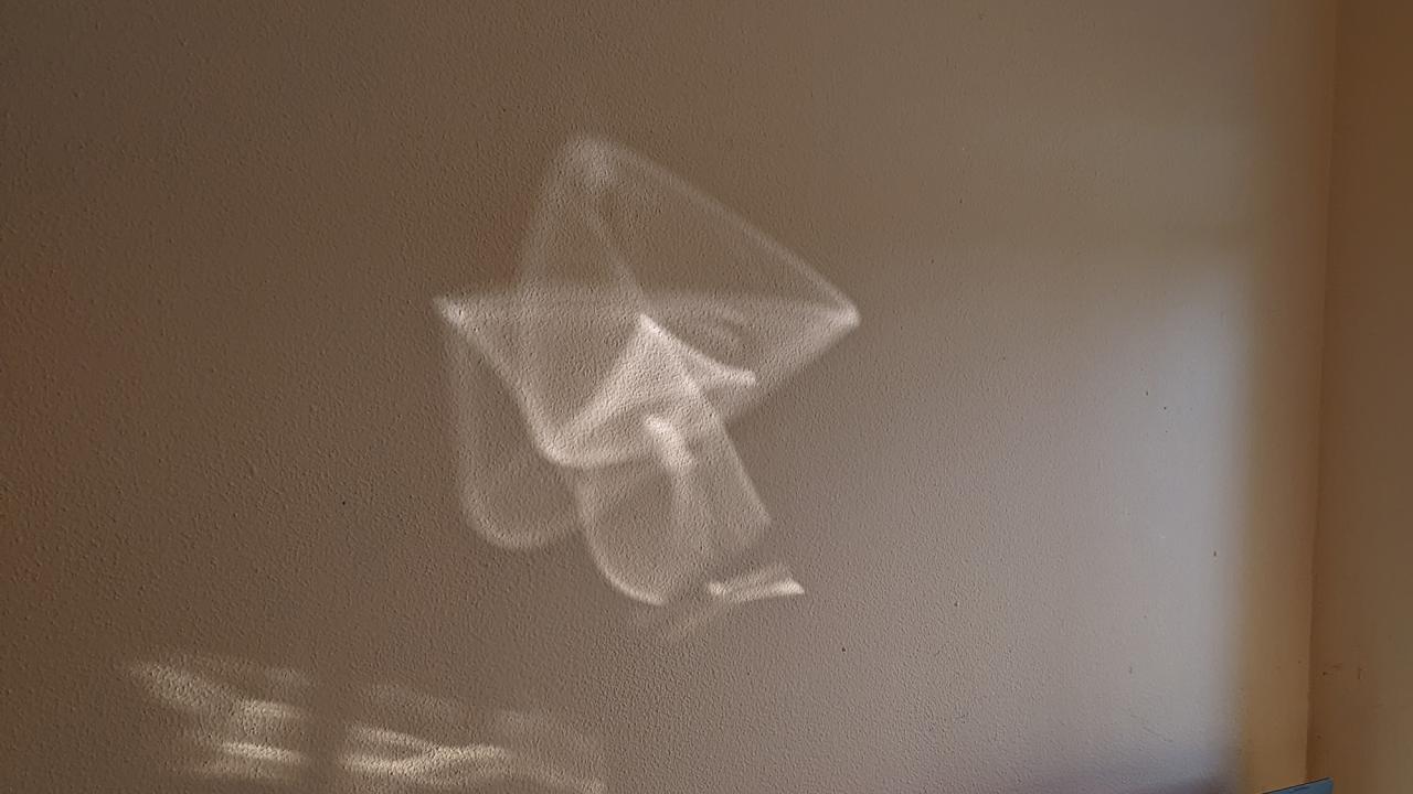 A white geometric pattern on a brown textured wall. 