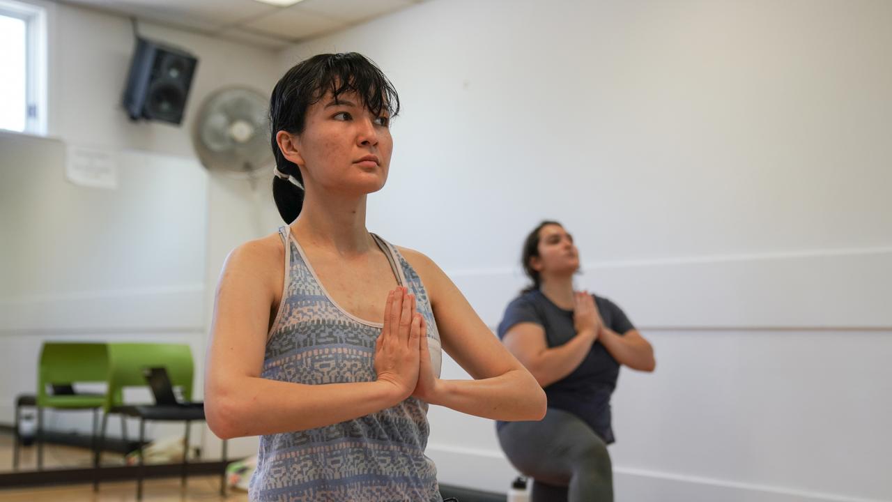 Alison Rader, in the foreground, and Nezrin Hasanly, in the background, are in the yoga prayer position. is in the yoga prayer pose and Nezrin 