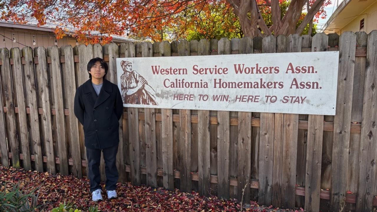 Seito Ezawa poses next to a sign for the Western Service Workers Association