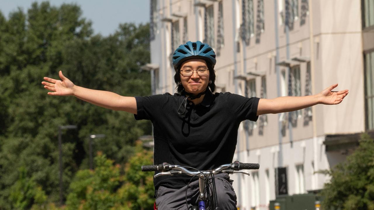 Sen Tabofunda rides a bike with her arms outstretched