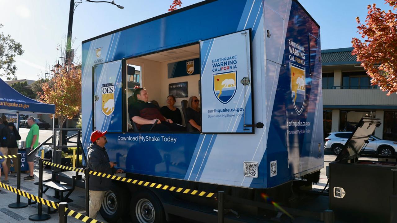 Three people are seated in the Cal OES shake trailer