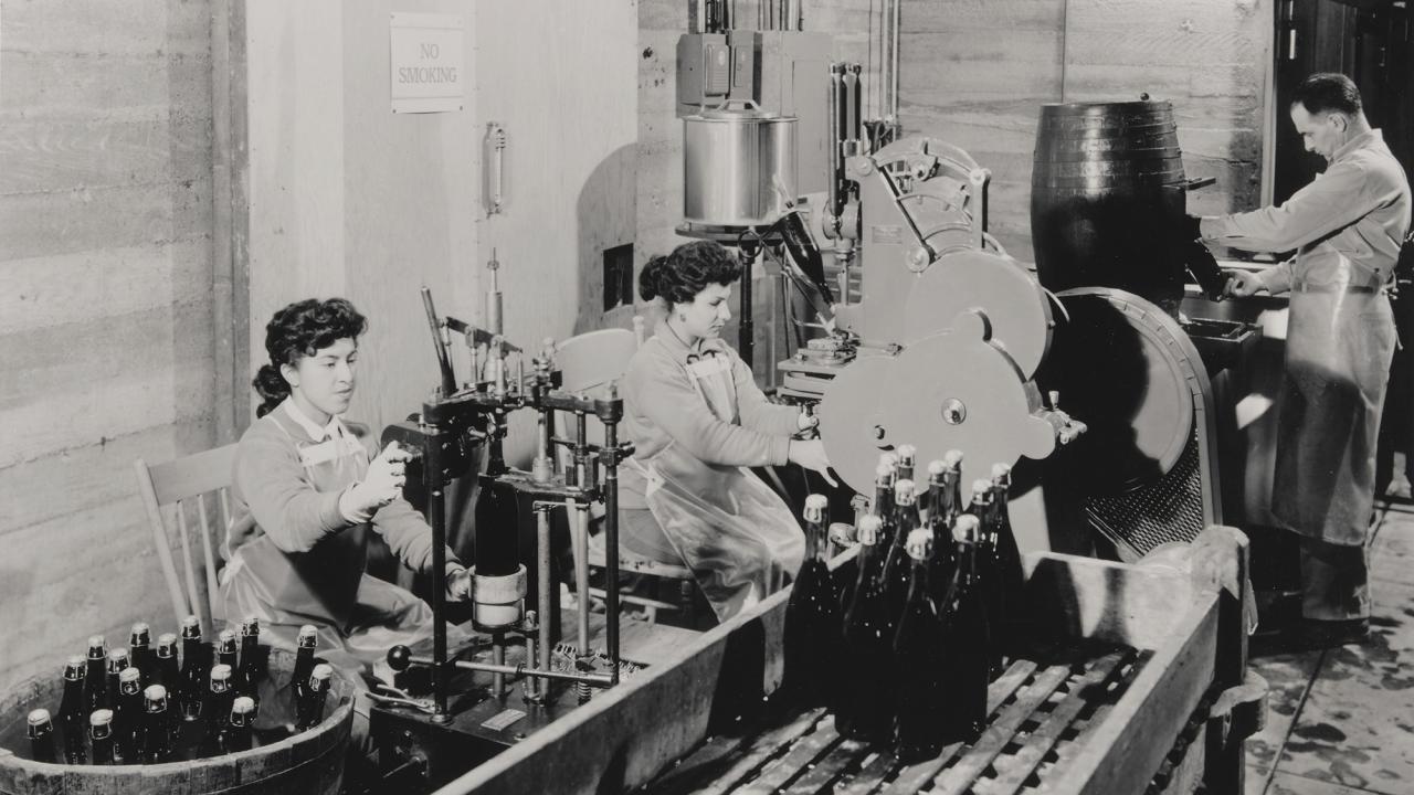 Two women and a man are pictured as sparkling wine is bottled at Beaulieu Vineyard in the 1950s