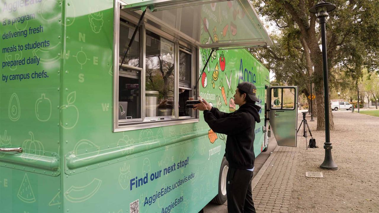A student picks up a meal from a green food truck