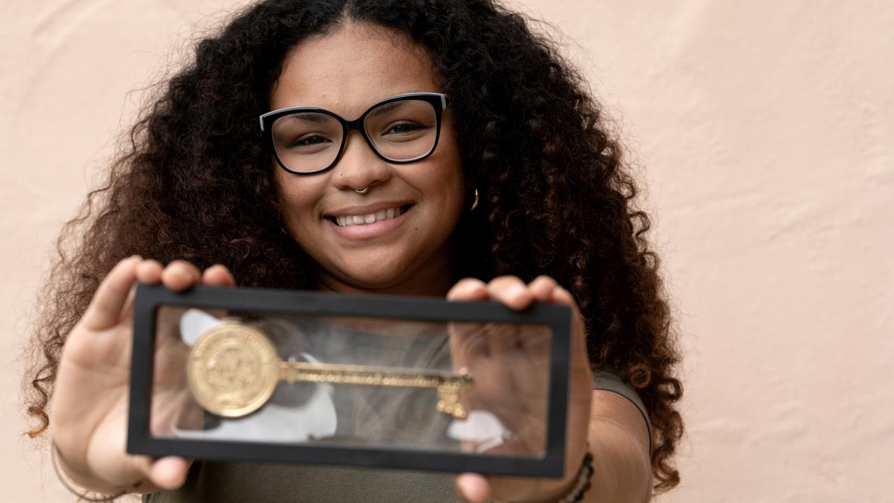 Student Natasha Bibbs holds a framed key to the city of Donaldsonville, Louisiana, in front of her