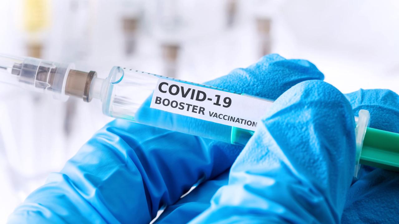 Syringe labeled "COVID-19 booster vaccination"