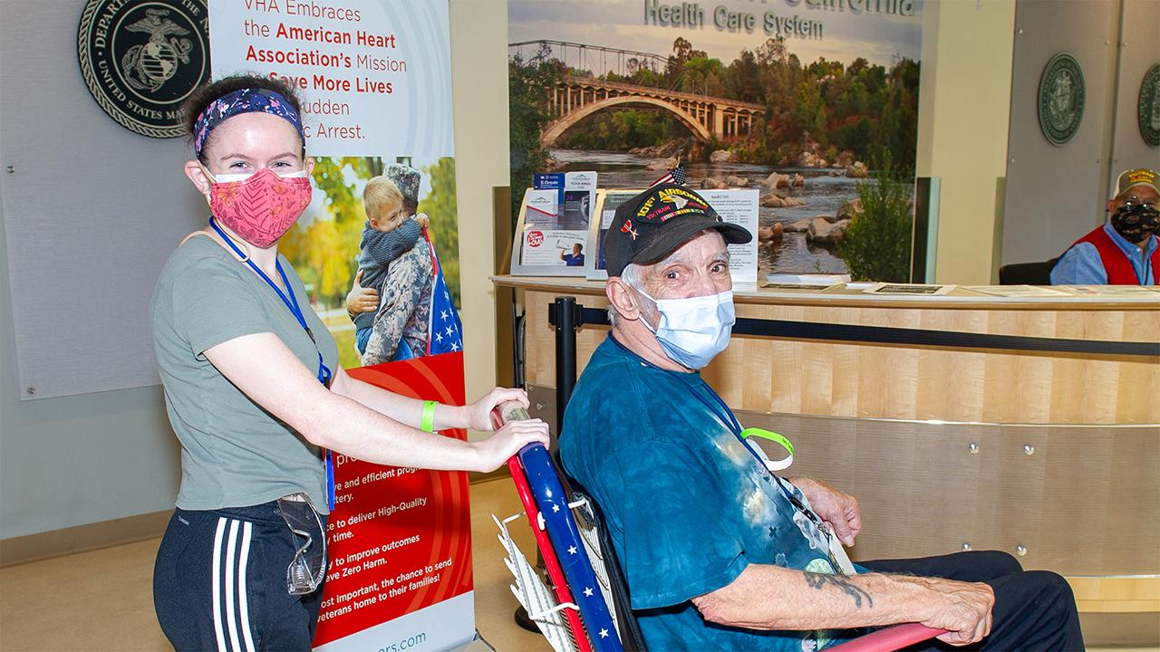 Madeline Bright pushes a wheelchair with a patient in it.