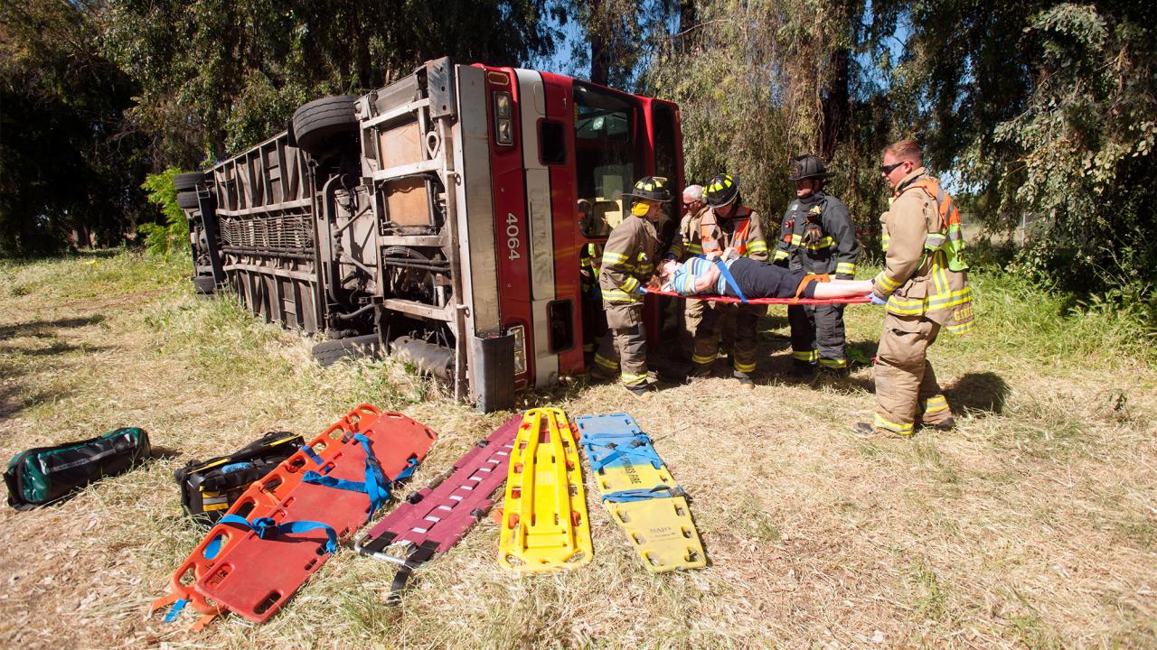 Firefighters remove actor from bus that is rolled over on its side for training incident.