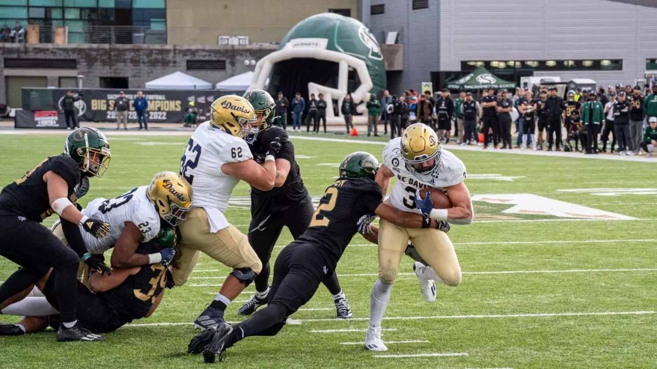 football player runs with ball while others try to tackle him.