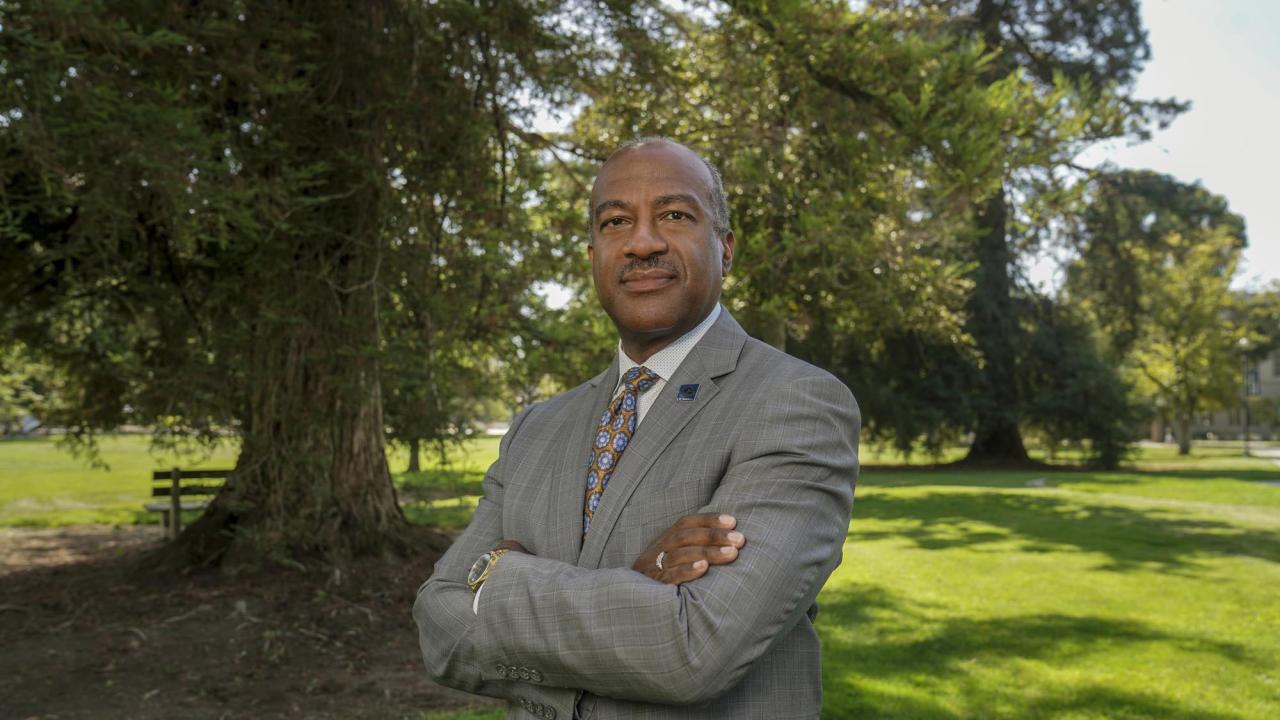 Chancellor Gary S. May, arms folded, on the Quad