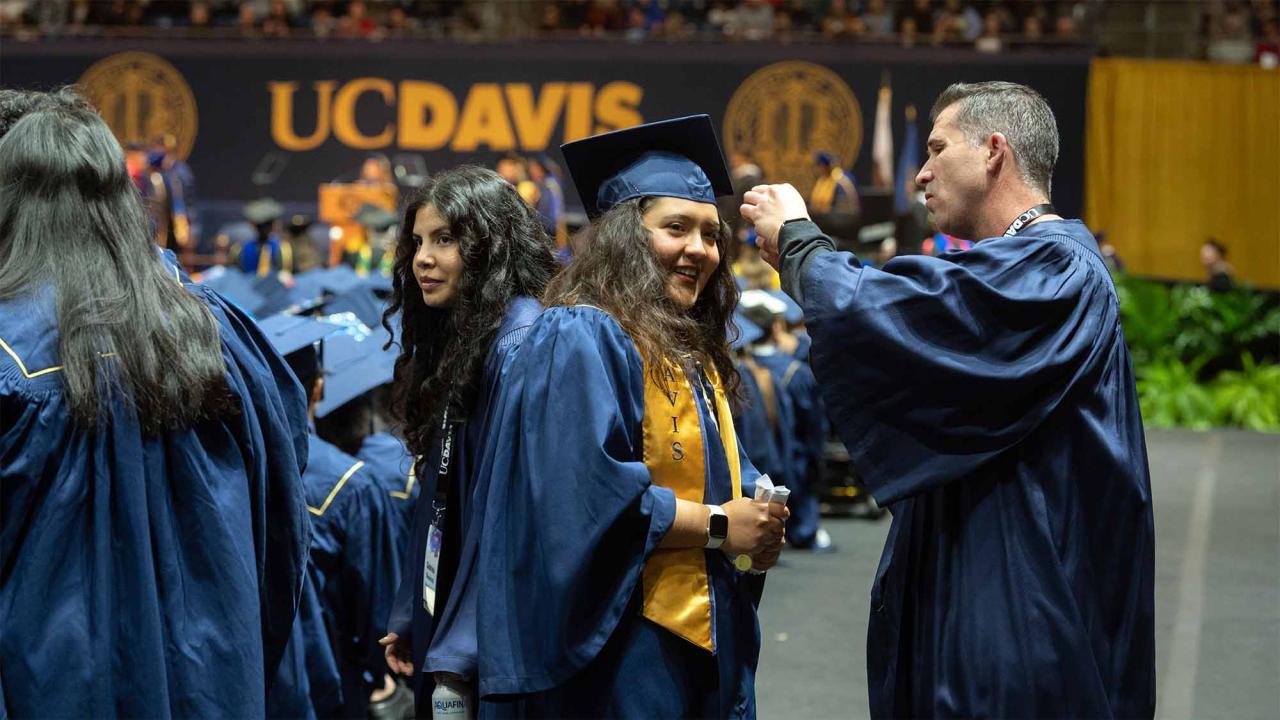 Person helps adjust graduation cap on student