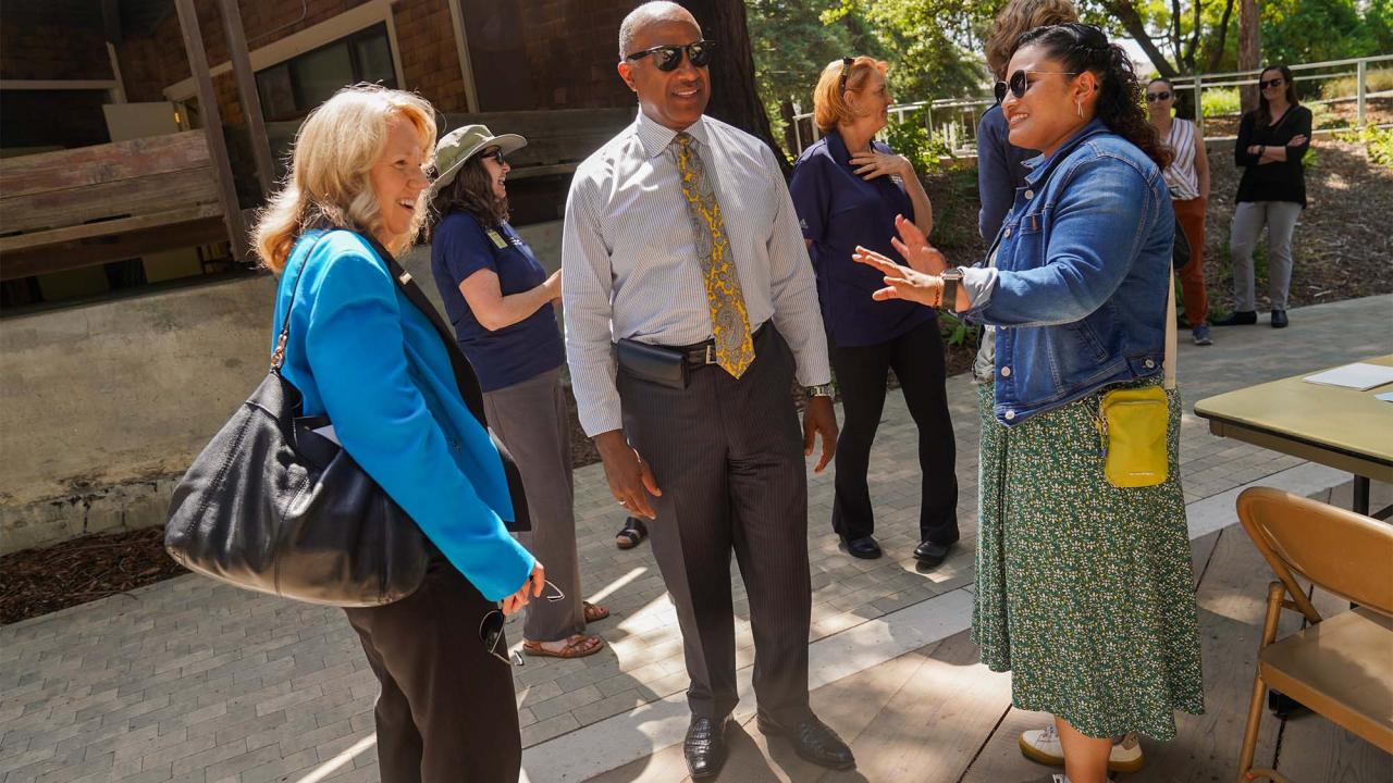 Mary Croughan and Gary S. May speak to a staffer on Wyatt Deck.
