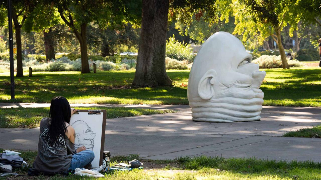 Student sits and sketches Eye on Mrak Egghead.