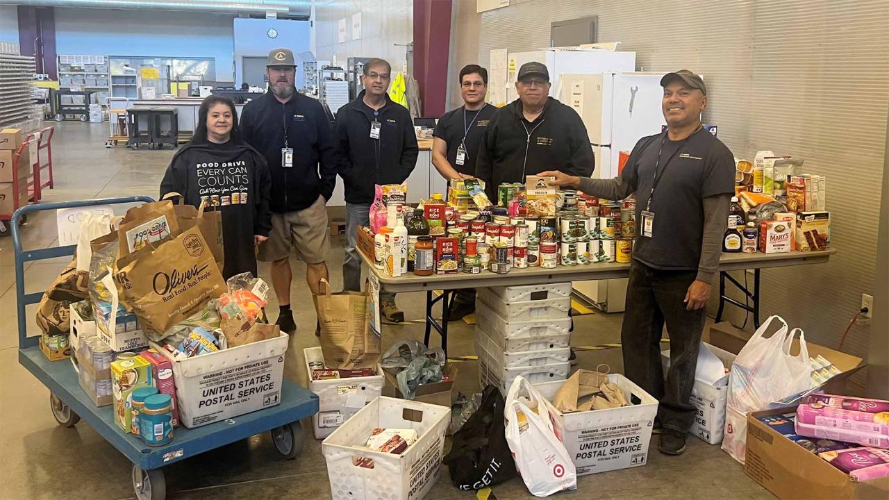 People pose for photo next to food collected for a food drive