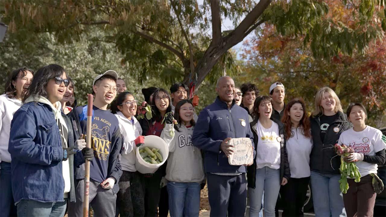 Chancellor Gary S. May poses for photo with group of students at garden cleanup event.