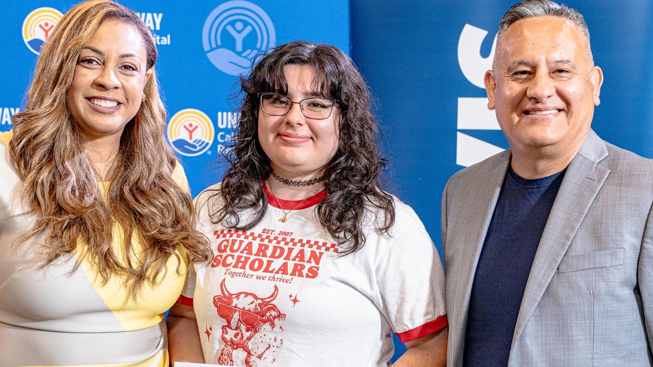 Two women and a man stand shoulder to shoulder
