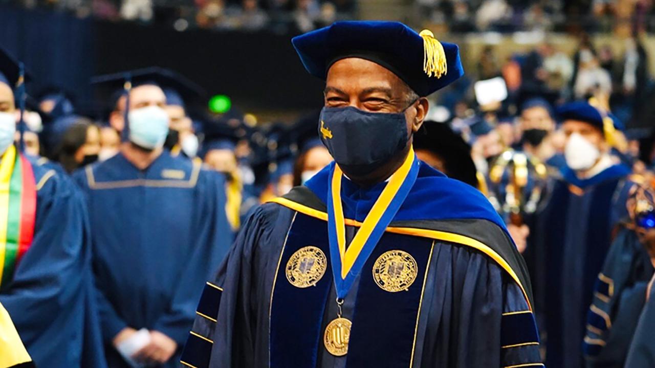 In full academic regalia, Chancellor Gary S. May strides through graduates