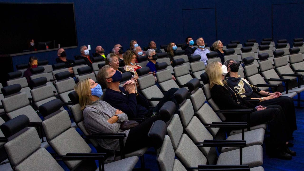 People sit in a dark planetarium