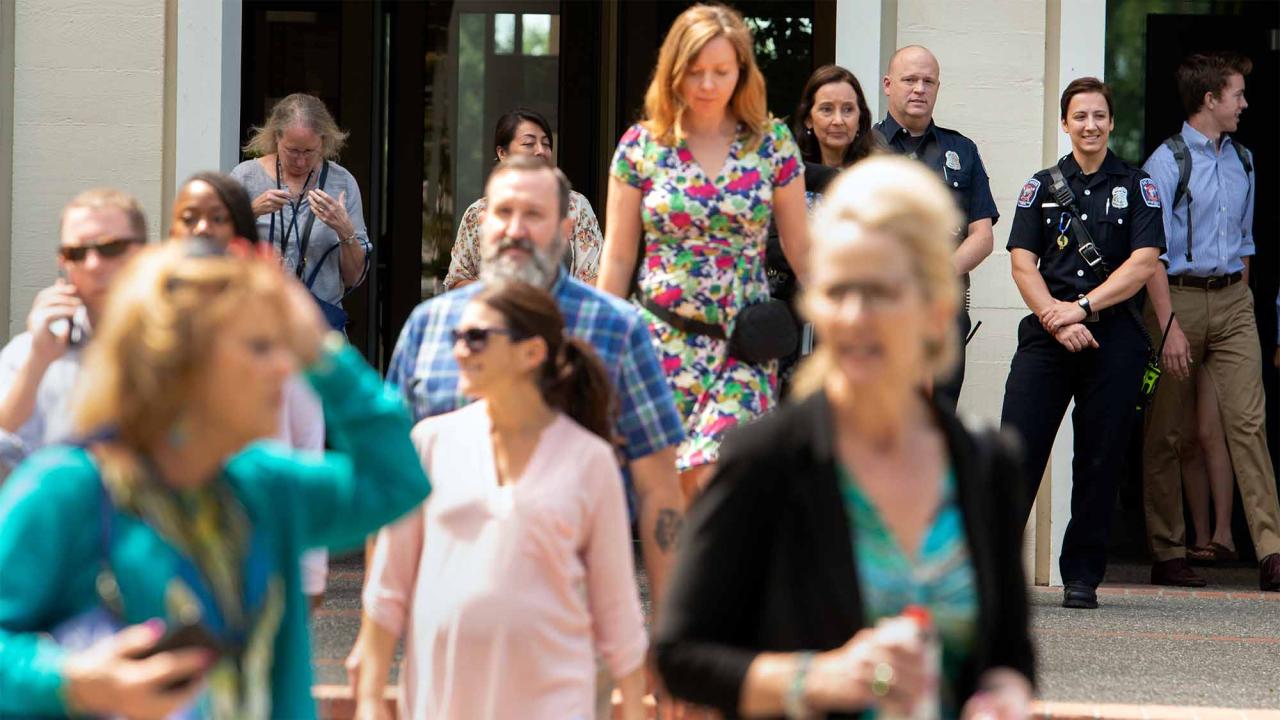 People leave Mrak Hall as firefighters watch.