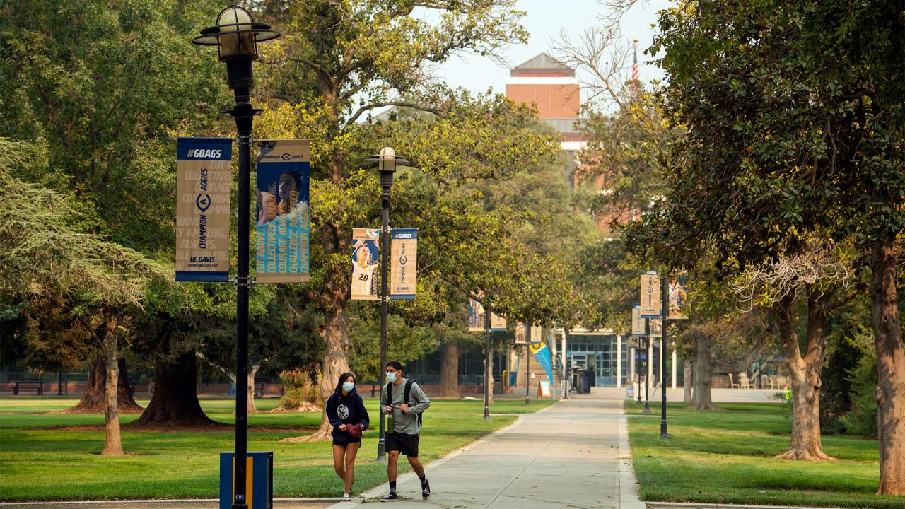 Two people walking on Centennial Walk, near the Quad.